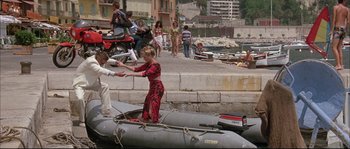 Movie still from “The Jewel of the Nile” (1985), directed by Lewis Teague – A woman in a red and black dress is on a boat; Wide shot, High angle