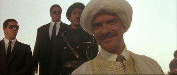 Movie still from “The Jewel of the Nile” (1985), directed by Lewis Teague – A group of men standing next to each other; Close Up shot, Low angle