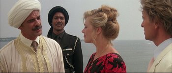 Movie still from “The Jewel of the Nile” (1985), directed by Lewis Teague – A man and a woman standing next to each other on a beach; Close Up shot, Over the shoulder angle