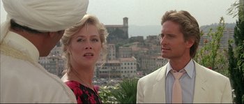 Movie still from “The Jewel of the Nile” (1985), directed by Lewis Teague – A man and a woman standing next to each other in front of a city; Close Up shot, Low angle
