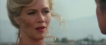 Movie still from “The Jewel of the Nile” (1985), directed by Lewis Teague – A woman with blonde hair; Close Up shot, Over the shoulder angle