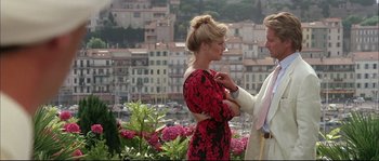 Movie still from “The Jewel of the Nile” (1985), directed by Lewis Teague – A man and a woman standing next to each other in front of a city; Medium shot, Low angle
