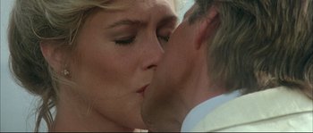 Movie still from “The Jewel of the Nile” (1985), directed by Lewis Teague – A person kissing another person on the cheek; Close Up shot, Over the shoulder angle