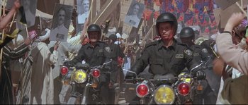 Movie still from “The Jewel of the Nile” (1985), directed by Lewis Teague – Two police officers on motorcycles in front of a crowd of people; Wide shot, High angle