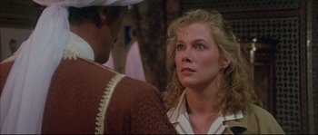 Movie still from “The Jewel of the Nile” (1985), directed by Lewis Teague – A person looking at a person; Close Up shot, Over the shoulder angle