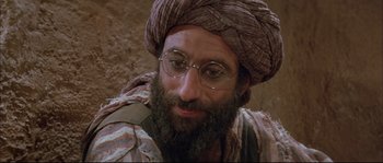 Movie still from “The Jewel of the Nile” (1985), directed by Lewis Teague – A man with a beard wearing a turban and wearing glasses; Close Up shot, High angle