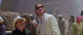 Movie still from “The Jewel of the Nile” (1985), directed by Lewis Teague – A man in a white suit and sun glasses; Close Up shot, Low angle