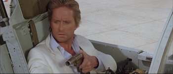 Movie still from “The Jewel of the Nile” (1985), directed by Lewis Teague – A person holding a gun; Close Up shot, Over the shoulder angle