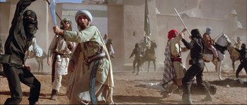 Movie still from “The Jewel of the Nile” (1985), directed by Lewis Teague – A group of people in a desert area; Wide shot, Over the shoulder angle