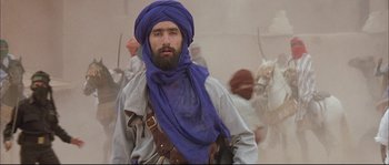 Movie still from “The Jewel of the Nile” (1985), directed by Lewis Teague – A man with a beard and a blue turban; Medium shot, Low angle