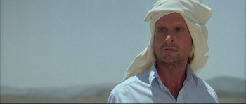 Movie still from “The Jewel of the Nile” (1985), directed by Lewis Teague – A person with a towel on his head; Close Up shot, Over the shoulder angle
