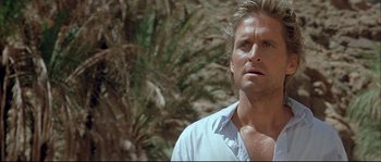 Movie still from “The Jewel of the Nile” (1985), directed by Lewis Teague – A person wearing a white shirt near a palm tree; Close Up shot, Low angle