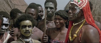 Movie still from “The Jewel of the Nile” (1985), directed by Lewis Teague – A group of people standing around each other; Close Up shot, Over the shoulder angle