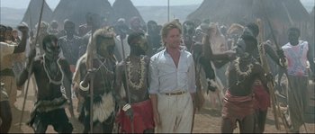 Movie still from “The Jewel of the Nile” (1985), directed by Lewis Teague – A group of people standing in a field; Wide shot, Over the shoulder angle