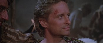 Movie still from “The Jewel of the Nile” (1985), directed by Lewis Teague – A person with a scar on their face; Close Up shot, Over the shoulder angle