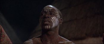 Movie still from “The Jewel of the Nile” (1985), directed by Lewis Teague – A man with white markings on his face; Close Up shot, Low angle
