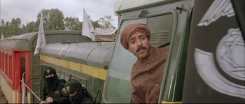 Movie still from “The Jewel of the Nile” (1985), directed by Lewis Teague – A man with a turban is looking out of a train window; Medium shot, Low angle