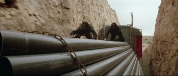 Two men in black jackets are climbing a wall