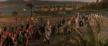 Movie still from “The Jewel of the Nile” (1985), directed by Lewis Teague – A group of people riding bikes down a dirt road; Extreme Wide shot, High angle