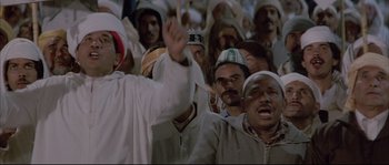 Movie still from “The Jewel of the Nile” (1985), directed by Lewis Teague – A group of people standing in front of each other; Medium shot, Low angle