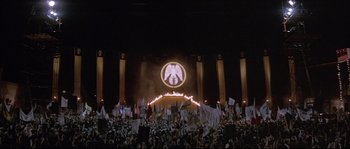 Movie still from “The Jewel of the Nile” (1985), directed by Lewis Teague – A crowd of people standing in front of an illuminated sign; Extreme Wide shot, High angle
