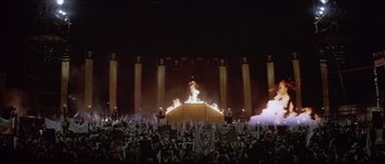 Movie still from “The Jewel of the Nile” (1985), directed by Lewis Teague – A crowd of people standing in front of a stage; Extreme Wide shot, High angle