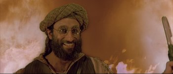 Movie still from “The Jewel of the Nile” (1985), directed by Lewis Teague – A man with a beard wearing a turban and glasses; Close Up shot, Low angle