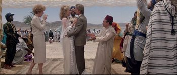 Movie still from “The Jewel of the Nile” (1985), directed by Lewis Teague – A man and a woman kissing on the beach; Wide shot, Over the shoulder angle