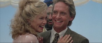 Movie still from “The Jewel of the Nile” (1985), directed by Lewis Teague – A man and a woman laughing with a man in the background; Close Up shot, Low angle