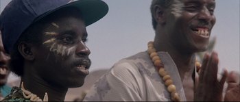 Movie still from “The Jewel of the Nile” (1985), directed by Lewis Teague – Two men are standing next to each other; Close Up shot, Low angle