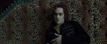 Movie still from “Queen of the Damned” (2002), directed by Michael Rymer – A man in black jacket sitting on a leopard print couch; Medium shot, Over the shoulder angle