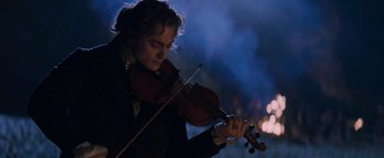 Movie still from “Queen of the Damned” (2002), directed by Michael Rymer – A man is playing a violin in the dark; Close Up shot, Low angle