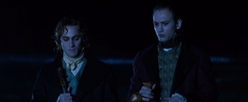 Movie still from “Queen of the Damned” (2002), directed by Michael Rymer – Two men are standing in the dark holding something; Medium shot, Low angle