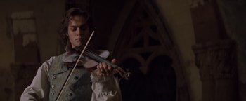 Movie still from “Queen of the Damned” (2002), directed by Michael Rymer – A young man playing a violin in a dark room; Medium shot, Low angle
