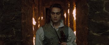 Movie still from “Queen of the Damned” (2002), directed by Michael Rymer – A young man holding a violin in front of fire; Medium shot, Low angle