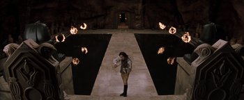 Movie still from “Queen of the Damned” (2002), directed by Michael Rymer – A woman holding a violin standing in front of a pool of fire; Extreme Wide shot, Overhead angle