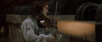 Movie still from “Queen of the Damned” (2002), directed by Michael Rymer – A man playing a violin in a room; Medium shot, Low angle