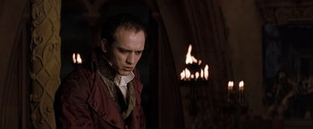 Movie still from “Queen of the Damned” (2002), directed by Michael Rymer – A man in a red jacket standing in front of a fire; Medium shot, Low angle