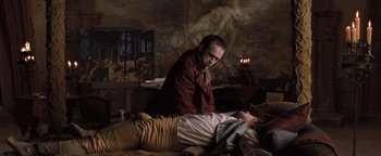 Movie still from “Queen of the Damned” (2002), directed by Michael Rymer – A man and a woman laying on a bed in front of a painting; Medium shot, High angle