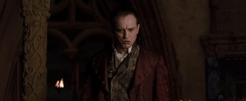 Movie still from “Queen of the Damned” (2002), directed by Michael Rymer – A man in a red coat and a brown tie; Medium shot, Low angle