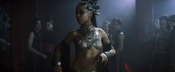 Movie still from “Queen of the Damned” (2002), directed by Michael Rymer – A woman in a costume is standing next to a group of people; Medium shot, High angle