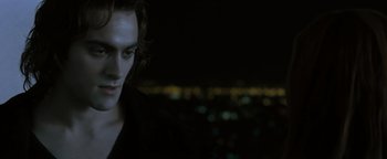 Movie still from “Queen of the Damned” (2002), directed by Michael Rymer – A man with long hair standing in front of a city at night; Close Up shot, Over the shoulder angle