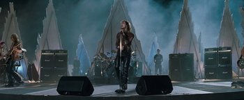Movie still from “Queen of the Damned” (2002), directed by Michael Rymer – A man is singing on a stage in front of a group of people; Wide shot, Low angle
