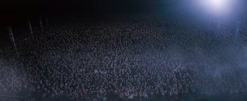 Movie still from “Queen of the Damned” (2002), directed by Michael Rymer – A large crowd of people in a stadium at night; Extreme Wide shot, High angle