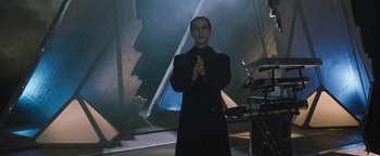 Movie still from “Queen of the Damned” (2002), directed by Michael Rymer – A man in a black coat standing in front of stairs; Medium shot, Low angle