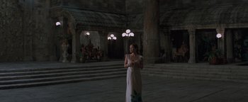 A woman in a long white dress standing in an indoor setting