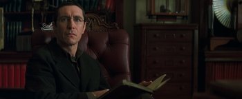 Movie still from “Queen of the Damned” (2002), directed by Michael Rymer – A man sitting in a chair holding an open book; Close Up shot, Over the shoulder angle