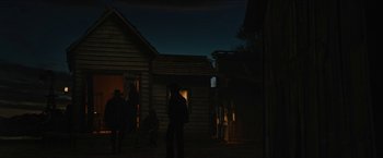 Movie still from “The Kid” (2019), directed by Vincent D'Onofrio – A group of people standing in front of a wooden house; Wide shot, Low angle