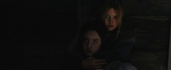 Movie still from “The Kid” (2019), directed by Vincent D'Onofrio – Two women in a dark room looking at the camera; Medium shot, Over the shoulder angle