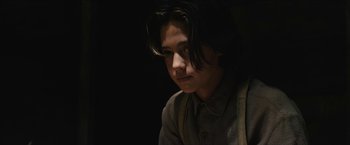 Movie still from “The Kid” (2019), directed by Vincent D'Onofrio – A man with long black hair is looking into the distance; Close Up shot, Over the shoulder angle